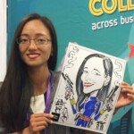 Woman holding a caricature drawing of herself featuring cartoon guns, standing in front of a blue event backdrop.