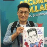 A man holds a caricature of himself dressed as Captain America at a business event booth.
