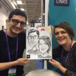 Two people smile and hold up a caricature drawing of themselves at an event, with a teal "Intralinks" sign behind them.