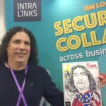 Man with curly hair holds a caricature of himself as Thor in front of a promotional banner at an event.