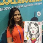 Woman holding a caricature of herself dressed as Wonder Woman, standing in front of a "Collaboration" banner.