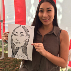 A woman sitting on a white chair holds a black-and-white caricature portrait of herself in front of a striped backdrop.