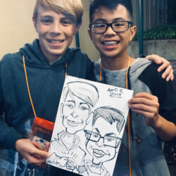 Two boys smiling and holding a caricature drawing of themselves dated April 5, 2019.