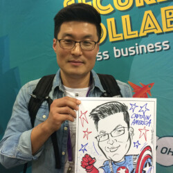 A man holding a caricature of himself as Captain America, standing in front of a business event backdrop.