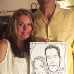 A smiling couple poses indoors, holding a caricature drawing of themselves at a 60th birthday celebration.
