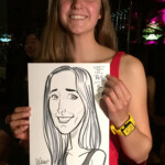 Young woman in a red dress smiles and holds a caricature portrait of herself at an indoor event.