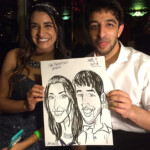 Two people smiling and holding a caricature portrait of themselves at an event, dated April 7, 2016.