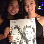 Two women smiling and holding a caricature drawing of themselves at an event, dated April 7, 2016.