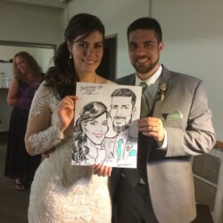 Bride and groom in wedding attire smile while holding a caricature portrait of themselves dated September 30, 2017.