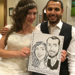 A bride and groom in wedding attire hold a caricature portrait of themselves and smile at the camera.