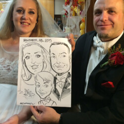 Bride and groom in wedding attire hold a caricature drawing of themselves and a child, dated November 28, 2015.