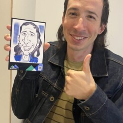 A person smiling gives a thumbs up and holds a caricature drawing resembling themselves.